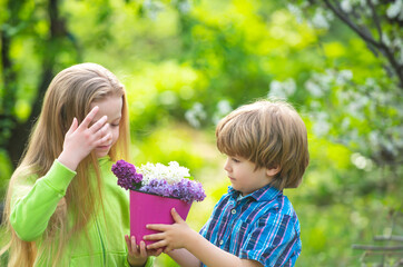 Obraz premium Spring kids smiling in garden with flowers. Spring garden teamwork with brother and sister. Spring gardening moment with fresh plant. Spring garden fun and nature.