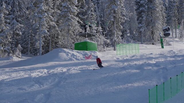 Freestyle Skier Descends Snowy Slope. Skier Navigates Terrain Park With Energetic Jumps And Sprays Snow. Adventurous Freestyle Skier Executes Aerial Stunts Through Snowy Bumpfilled Landscape