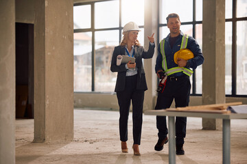 Obraz premium Female real estate developer and worker talking while examining construction progress.