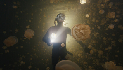Night freediving. Freediver swims underwater with jellyfish in the lake in Papua, Indonesia © Dudarev Mikhail