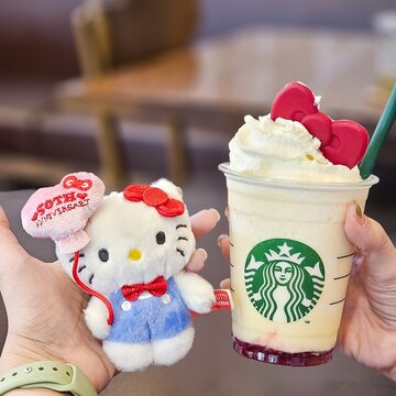 Person Holding Starbucks Frappuccino Decorated with Red Ribbon Chocolate Alongside Hello Kitty Sanrio 50th Anniversary Plush Toy for Lifestyle Content on October 30, 2024 in Bangkok, Thailand