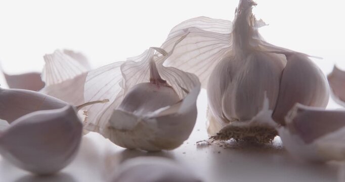 A pile of fresh garlic cloves closeup on a bright white background. High-key light. Selective focus. Slider shot.
