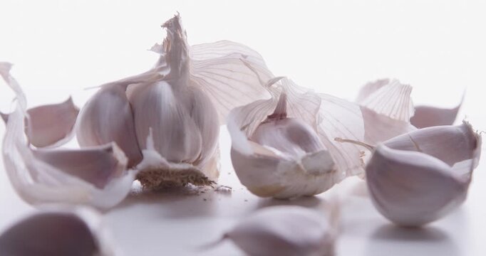 A pile of fresh garlic cloves closeup on a bright white background. High-key light. Selective focus. Slider shot.