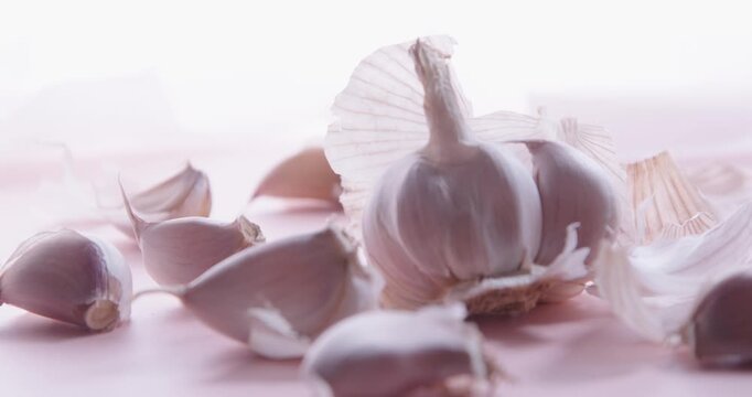 A pile of fresh garlic cloves closeup on a bright white background. High-key light. Selective focus. Slider shot.