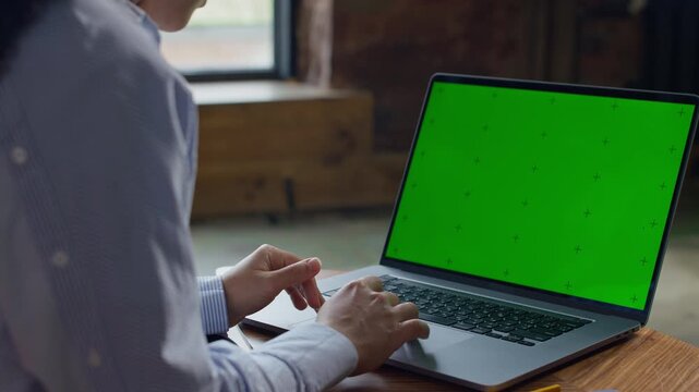 Person scrolling on laptop with green screen