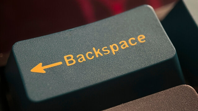 Close-up of computer keyboard backspace key with yellow text and arrow