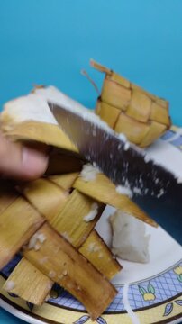 Sukabumi Regency, Indonesia - Close up of Blue plate holds traditional rice dish. Crispy, browned chunks sit beside soft white rice. Woven palm leaf bundle adds cultural touch. Bright blue background