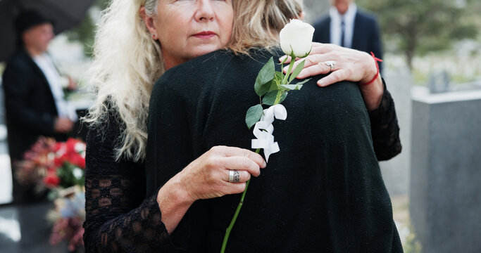 Woman, hug and funeral with rose for condolences, respect or mourning death together in cemetery. Female person, family and embrace with empathy or grief for farewell, burial or ceremony in graveyard