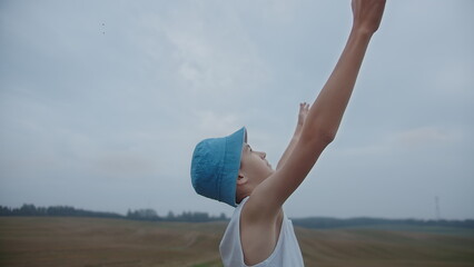 Boy Reaching Up Outdoors with Blue Hat in Field, have fun and enjoy