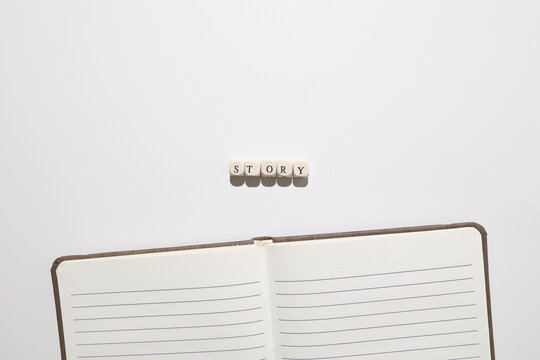 Word STORY spelled with letter tiles above an open notebook representing storytelling, writing, and creative narrative ideas.
