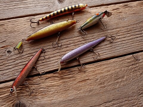 Close up of several fishing lures on a wooden table.