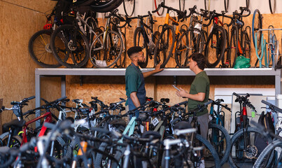 People managing bicycle inventory in sustainable store © PintoArt