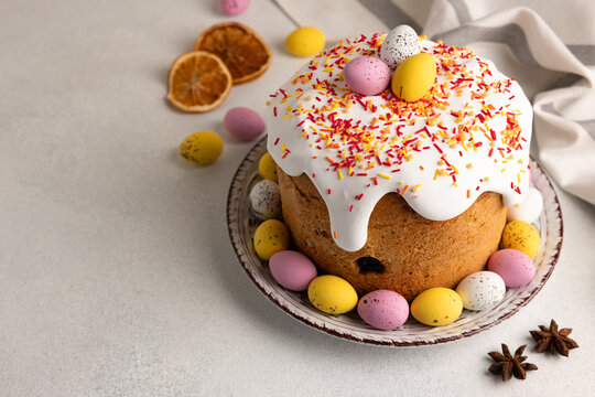 Traditional Easter cake decorated with white icing, colorful sprinkles, and pastel eggs and served on a beautiful plate, with copy space for your text.