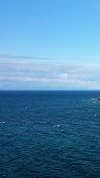 Expansive view of deep blue sea meeting the sky with a rocky coastline visible on the right, captured near Koroni, Greece.