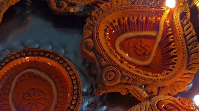 A close-up view of beautifully crafted terracotta diyas on a steel plate, ready for Diwali pujan. The intricate designs and warm clay textures perfectly capture the essence of the festival of lights.