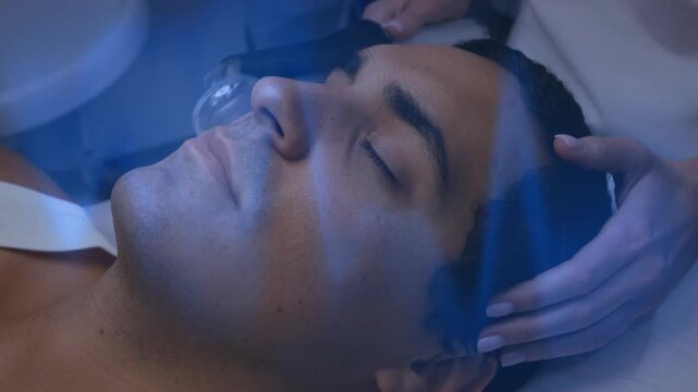 Vertical video: Spa pro placing blue glass tip near nose, gliding wand down cheek to jaw for facial