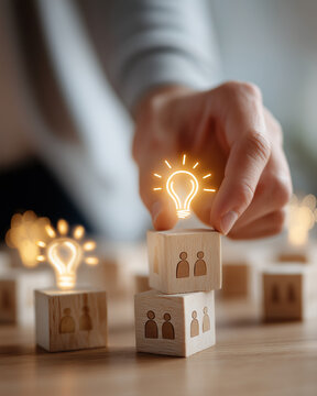 Illuminating the Core Idea: A hand strategically places a lightbulb symbol atop blocks symbolizing teamwork, creativity and innovative concepts.