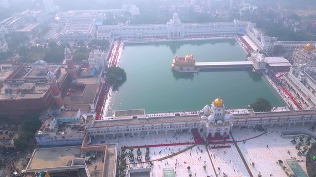 Aerial view of the stunning golden temple, a prominent sikh gurdwara in amritsar, punjab, india, showcasing its serene sarovar holy tank and white marble complex on a bright day