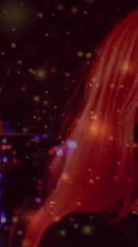 Vertical video: Female singer lifting mic and singing, sparks lighting bracelet during live music