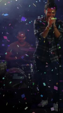 Vertical video: Lights, confetti showing singer holding mic, singing while drummer playing music