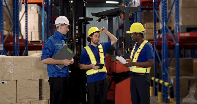 warehouse teamwork as african american forklift driver explains task to caucasian supervisor and coworker standing beside pallet and equipment during shipment coordination inside logistic facility