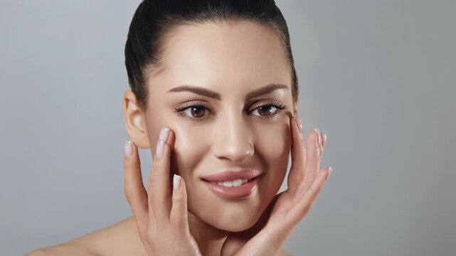 Woman applying skincare product on her face in a simple indoor setting during daytime