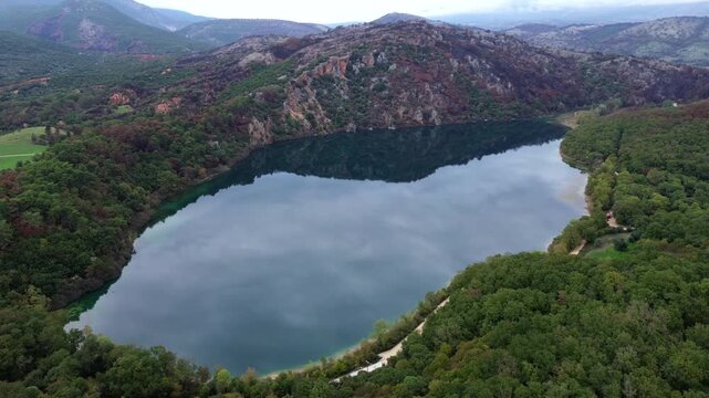 Cinematic drone orbit shot of Lake Ziros in Preveza. High-angle view showing beautiful cloud reflections on the calm, mirror-like water surface. Perfect for nature and travel visual storytelling.