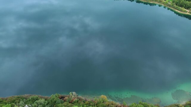 Cinematic aerial drone shot of Lake Ziros in Preveza, Greece. High-angle view of the deep blue water and lush forest reflection. Perfect for nature and travel visual storytelling.