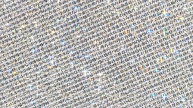 Seamless Rotating Silver Sparkling Crystals. Macro video of faceted rhinestones with intense bright star flares and smooth rotational camera movement on light surface in true seamless loop.