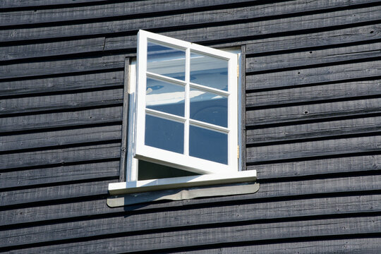 open wooden window in black clapboard wall