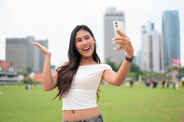 Cute woman smiling outdoors at Merdeka Square with Kuala Lumpur city skyline and a green park field