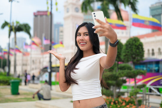 Thai Woman at Merdeka Square Kuala Lumpur using phone in front of the Sultan Abdul Samad Building.