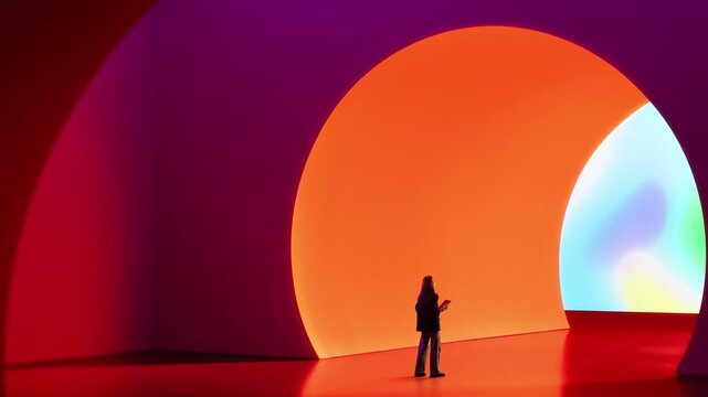 Woman holding tablet standing near large glowing circular structure in minimal environment. Concept of digital interaction, virtual portals, immersive systems and connected environments.