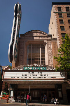 Facade of the Arlene Schnitzer Concert Hall with a marquee sign and a person changing letters in Portland, Oregon