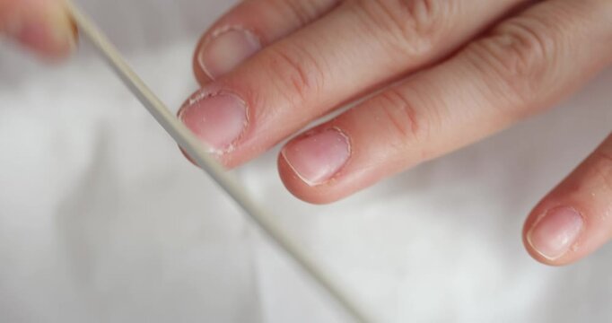 Closeup of a woman's hands using a nail file for a manicure at a white table