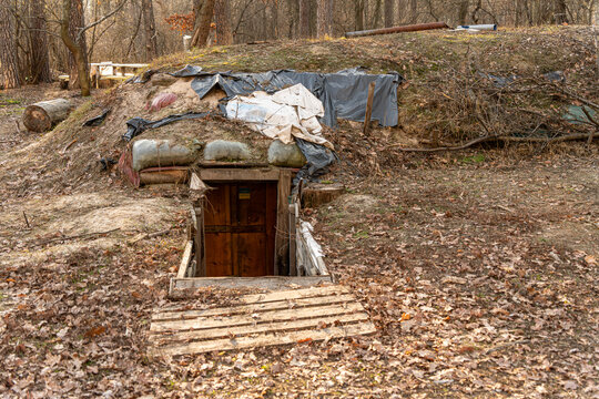 View of the hidden entrance to a rustic bunker, shrouded by earth and leaves, contrasts with the starkness of draped plastic, Kyiv, Kyiv City, Ukraine.