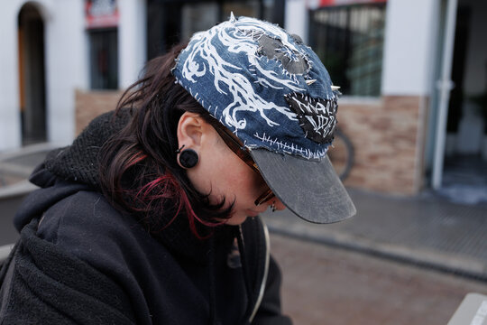 Perfil de una persona joven con gorra de estilo "punk" personalizada y dilatador en la oreja