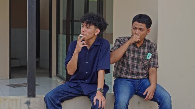 Smoker sits next to friend who reacts to secondhand smoke coughing and wearing medical mask