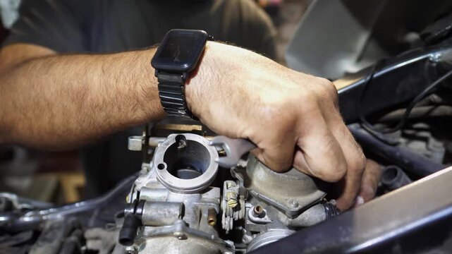Male hands of repairer fixing moto engine at workshop. Arms of professional mechanic repairing detail of motorcycle at workplace. Adult repairman mending vehicle motor at garage. Maintenance service