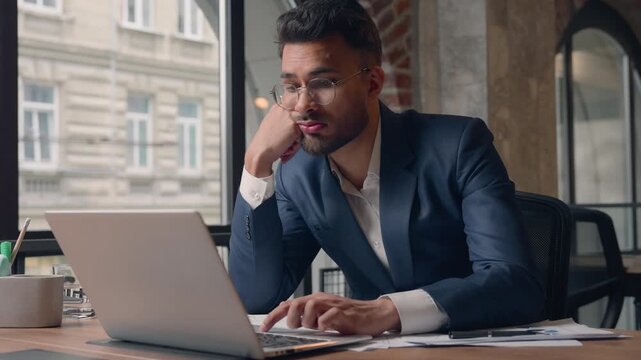 Arabian businessman suffering with routine monotonous laptop work business man Indian male guy startup CEO leader manager tired with boring work at office dissatisfied owner looking at computer screen