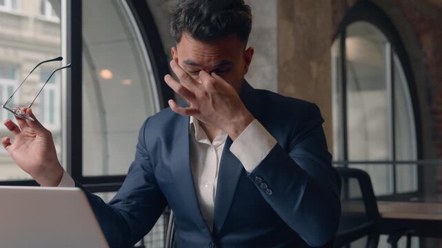 Arabian businessman feeling eyes discomfort Indian business man with computer Hindu guy male manager taking off glasses suffering dry eye pain working laptop at office sad with headache pain migraine