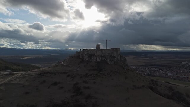 Spi&scaron; Castle, a medieval hilltop fortress in eastern Slovakia, dominates the rural landscape with its extensive stone ruins, defensive walls, and towers in this wide aerial panorama under a cloudy sky.