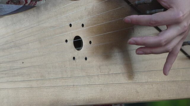 Gusli playing hands, traditional folk instrument performance close-up