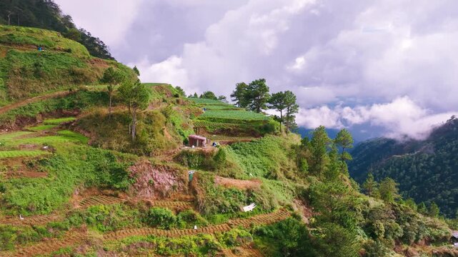 Terraced farms climb steep slopes beneath shifting mountain clouds