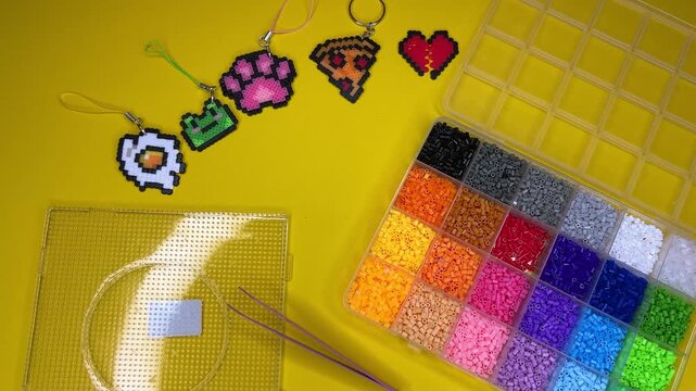 A horizontal video demonstrating a kit for making keychains at home using thermoplastic beads that need to be heated with an iron.