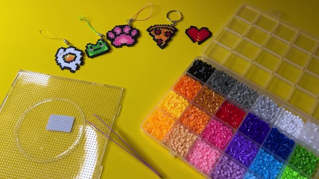 A horizontal video demonstrating a kit for making keychains at home using thermoplastic beads that need to be heated with an iron.