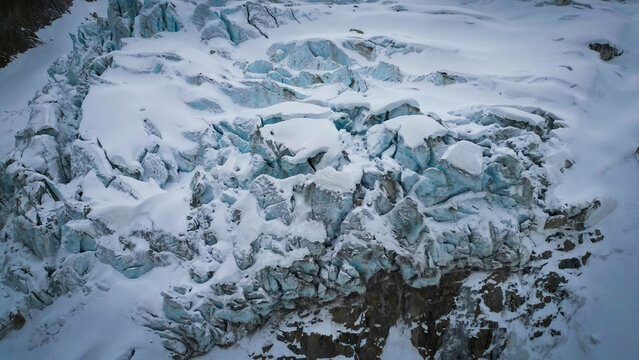 Aerial view of a glacial expanse, its icy facade dramatically etched against the stark, snow-covered landscape, Glacier d'Argentiere, Chamonix, Auvergne-Rhone-Alpes, France.