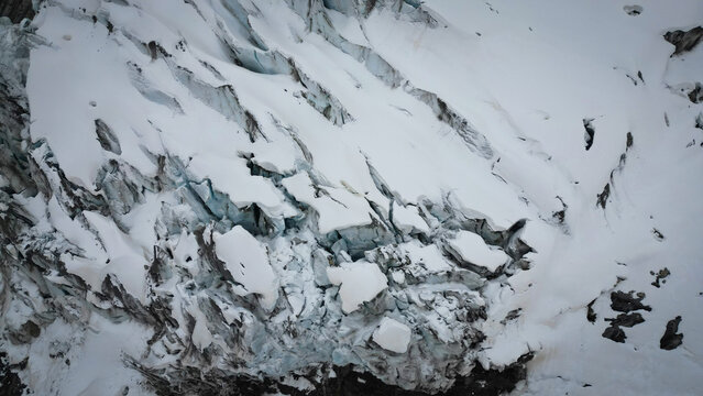 Aerial view of Glacier d'Argentiere's icy labyrinth, where snow-laden crevasses carve stark shadows, a frigid masterpiece, Chamonix, Auvergne-Rhone-Alpes, France.