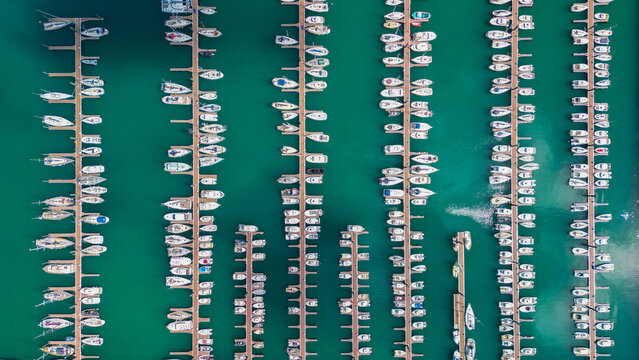 Aerial view of numerous white boats docked neatly in rows on the turquoise water of Port du Bloscon, creating a striking contrast, Roscoff, France.