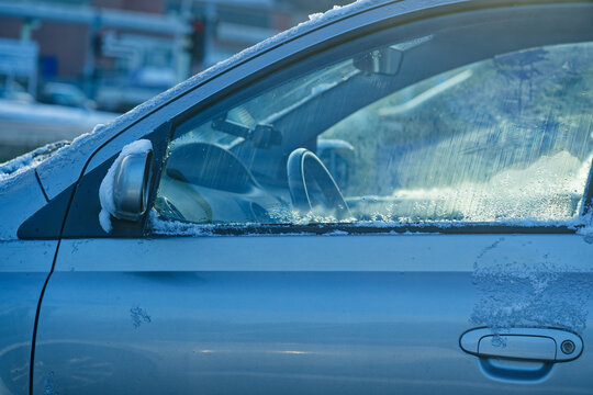 Frosted car window and door covered with snow on a cold winter day